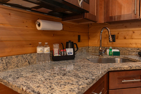 Granite countertop with a stainless steel sink and wooden cabinetry in a rustic kitchen setting