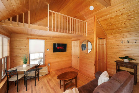 Cozy wood-paneled living area with a loft and dining nook.