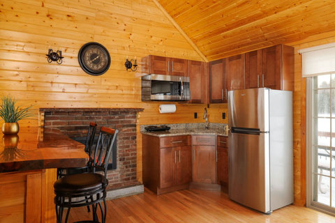rustic kitchen with wooden cabinetry, granite countertops, and a brick fireplace