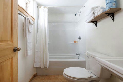 Simple bathroom with a bathtub and neatly arranged towels on a wooden shelf