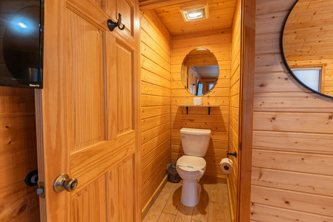 Cozy wooden bathroom with a round mirror and natural light.