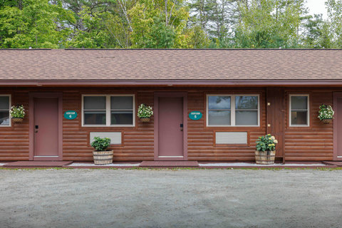 Exterior view of rustic cabin rooms surrounded by greenery.