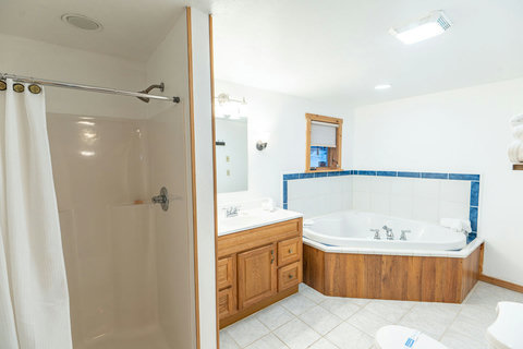 spacious bathroom featuring a corner jetted tub and separate shower with wood accents