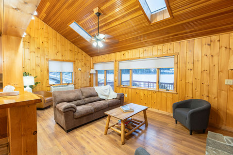 Cozy living room with wood-paneled walls and skylights providing natural light.