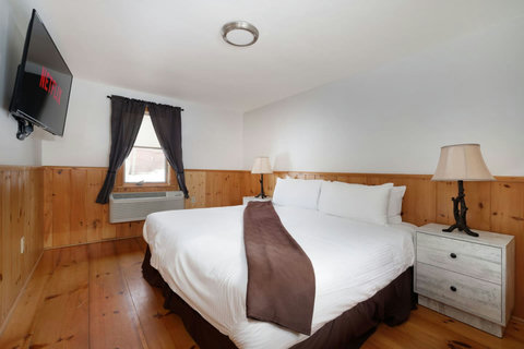 Cozy bedroom with wood paneling, a king-size bed, and a wall-mounted TV with streaming options.