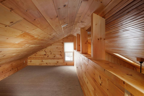 Cozy loft space with natural wood paneling and soft carpeting.