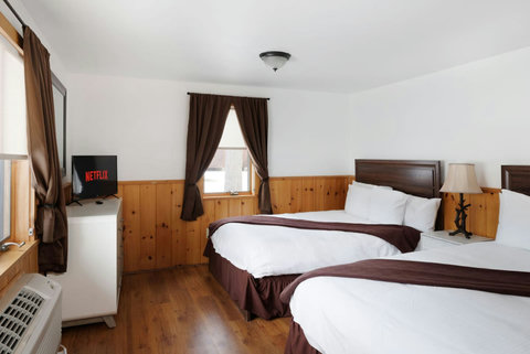 Cozy room with two queen beds, wood paneling, and a television with streaming options.