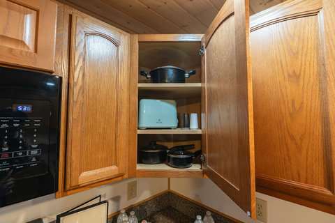 Corner kitchen cabinet with cookware and a toaster for convenient meal preparation.