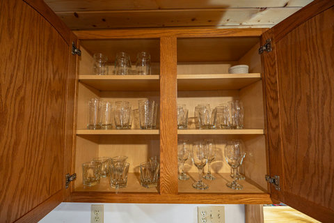 Organized wooden cabinet with a variety of glassware for guest use.