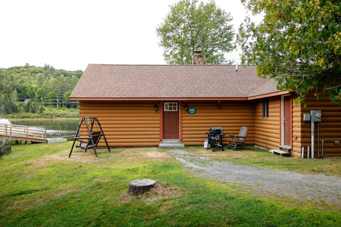 Rustic lakeside cabin with outdoor seating and a grill for relaxing by the water.