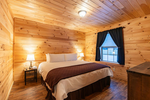 Cozy bedroom with wood-paneled walls and warm lighting for a rustic retreat.