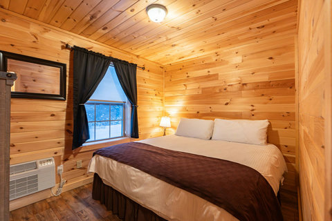 Cozy bedroom with wood-paneled walls and a large window for natural light.