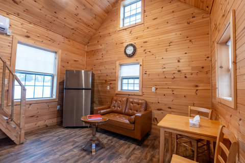 Cozy cabin interior with leather sofa, wooden dining table, and stainless steel refrigerator.