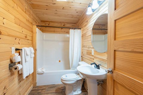 Rustic bathroom with wood paneling and a white bathtub and sink.