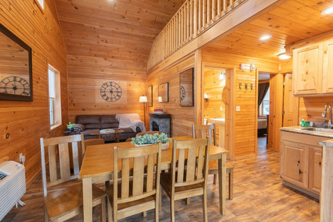 Cozy rustic dining and living area with vaulted ceilings and wood paneling.