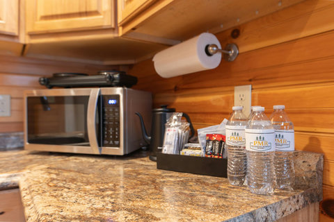Granite countertop with microwave and complimentary bottled water in a rustic kitchen setting.