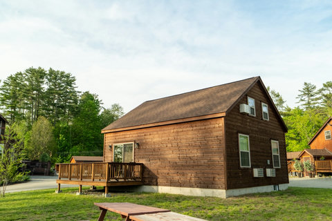 Rustic wooden cabin with a spacious deck surrounded by greenery.