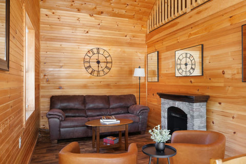Cozy living room with wood-paneled walls, a stone fireplace, and comfortable seating.