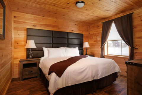 Cozy bedroom featuring wood-paneled walls and a large window with dark curtains.