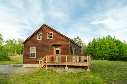 Rustic cabin with a spacious wooden deck surrounded by greenery