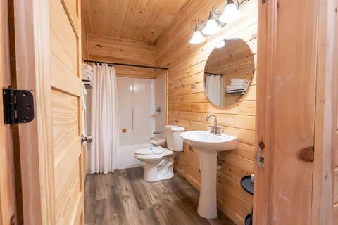 Rustic bathroom with wood-paneled walls and a bathtub with shower curtain.