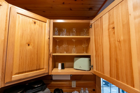 Open wooden cabinet with glassware and a retro-style toaster in a cozy kitchen setting