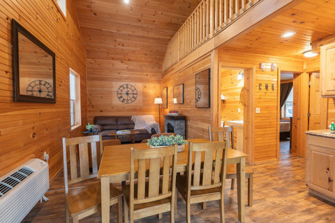Cozy rustic dining and living area with wood-paneled walls and vaulted ceilings.