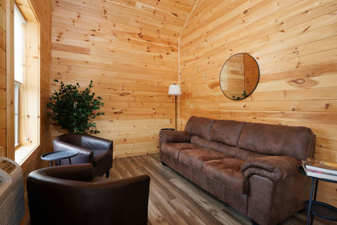 Cozy living area with leather seating and wood-paneled walls for a rustic atmosphere.