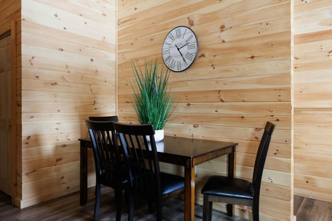 Cozy dining area with dark wood table and chairs against natural wood-paneled walls.