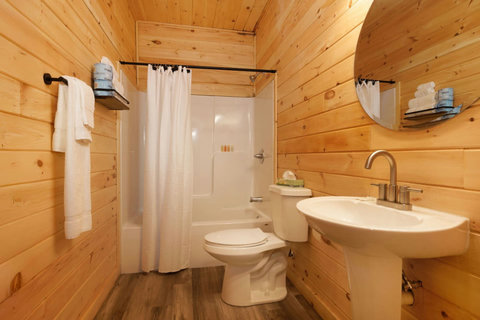 Rustic bathroom with wood-paneled walls and a shower-tub combination.