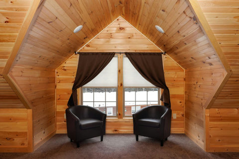 Cozy seating area with two black chairs by a window in a wood-paneled loft space