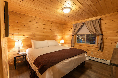 Cozy bedroom with wood-paneled walls and warm lighting for a relaxing stay.