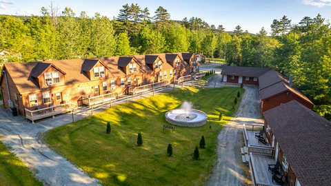 Rustic lodge-style accommodations surrounding a central courtyard with a fountain in a forested setting.