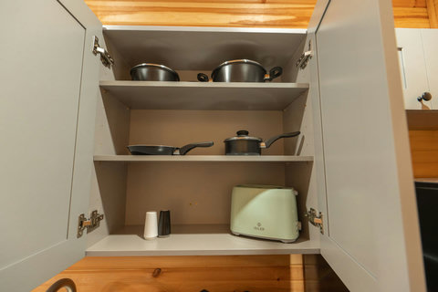 Open kitchen cabinet with cookware and a retro-style toaster for convenient meal preparation.