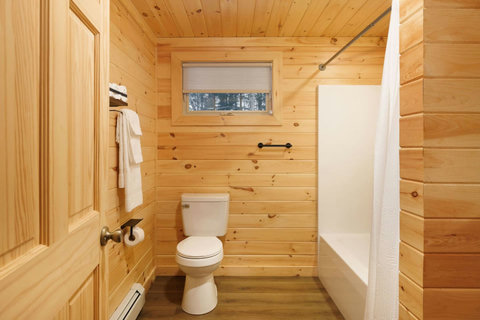Rustic bathroom with wood-paneled walls and a bathtub with shower curtain.
