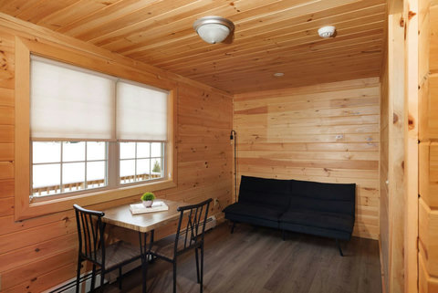 Cozy wood-paneled room with a small dining table and black sofa for relaxing.