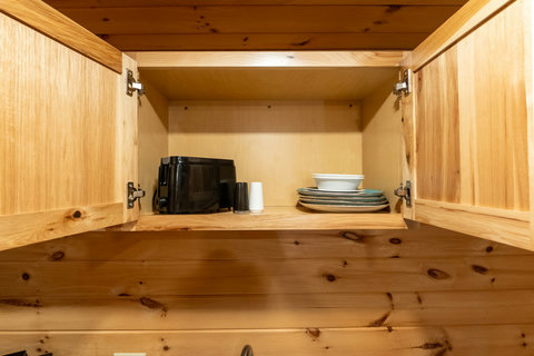 open wooden cabinet with plates, bowls, and a toaster inside