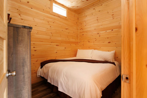 Cozy bedroom with natural wood walls and a comfortable bed.