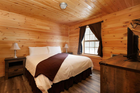 Cozy bedroom with wood-paneled walls and natural light from the window