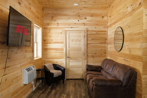 Cozy living area with wood-paneled walls, a leather sofa, and a wall-mounted television.