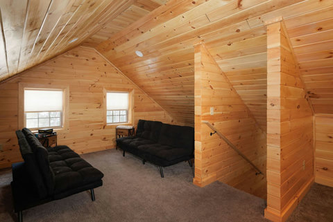 Cozy loft area with wood-paneled walls and two black futon sofas for relaxing.