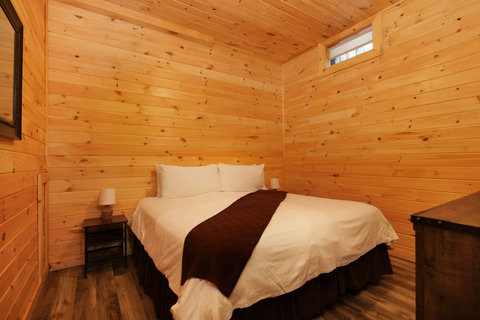 Cozy bedroom with wood-paneled walls and a king-size bed.