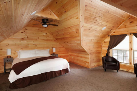 Cozy bedroom with wood-paneled walls and a large window seating area.