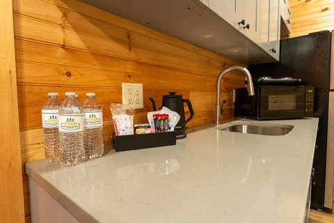 Modern kitchen countertop with a coffee station and stainless steel sink in a wood-paneled setting
