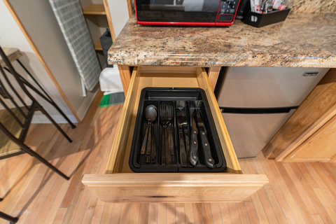 Kitchen drawer with essential cutlery neatly organized for guest use.