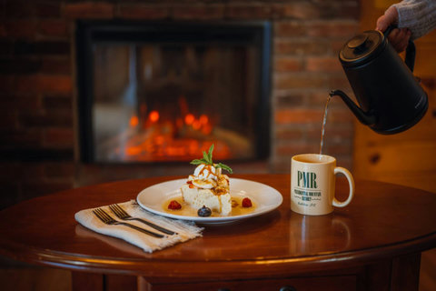 Cozy rustic setting with a warm fireplace, dessert, and tea being poured for a relaxing moment.