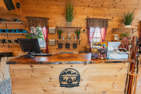 Rustic wooden front desk area with snacks and outdoor gear in a cozy lodge setting