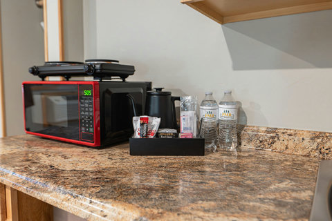 Compact kitchen counter with a microwave, hot plates, and complimentary beverages for convenience.