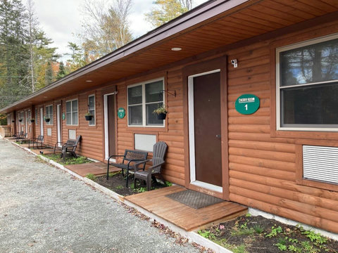 Exterior view of rustic rooms with outdoor seating in a wooded setting