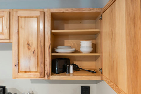 Open wooden kitchen cabinet with neatly arranged dishes and utensils